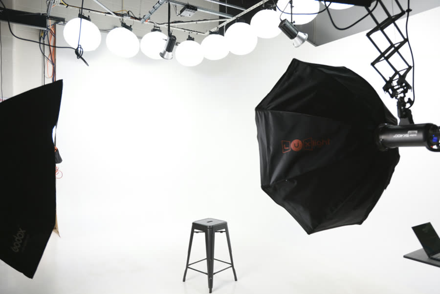 Studio A's white cyclorama sweep, lit by an overhead bank of soft lights and a black octagon softbox, with a stool at centre