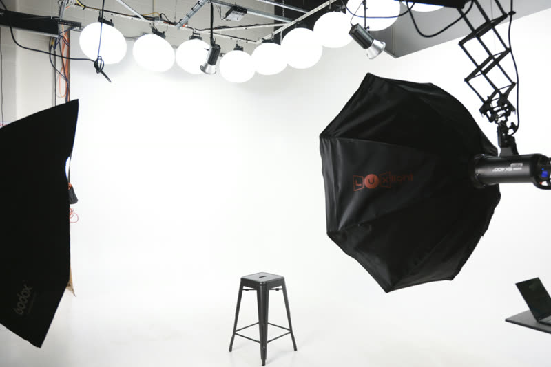 An empty Studio A set with softbox lighting and a stool ready for a shoot