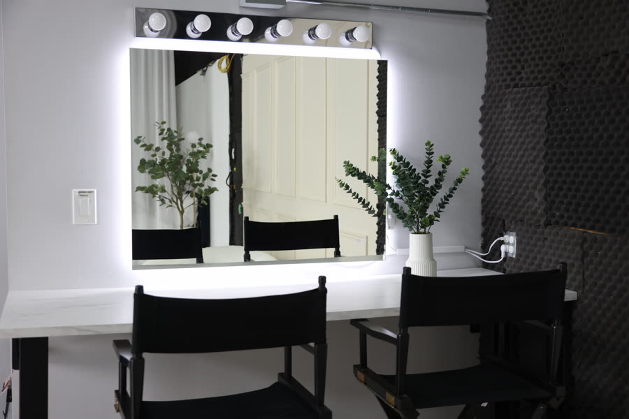 Studio A's makeup corner: a lit vanity mirror above a marble-topped counter, flanked by director's chairs